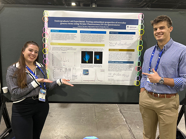 Two students, Autumn Thornton and Caleb Senters, smiling as they present their research poster at the 2026 American Chemical Society meeting.